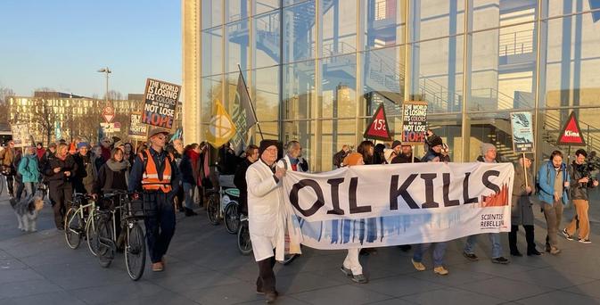 Aktivist:innen von Scientist Rebellion tragen ein Banner mit "OIL KILLS" bei einer Demonstration