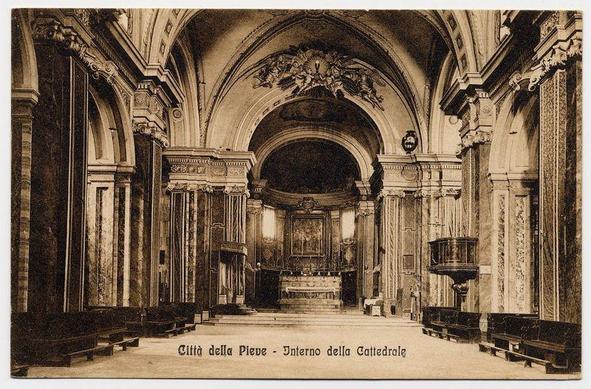 The image depicts an interior view of a church, captured in sepia tones suggesting it is either a historical photograph or artistically rendered to evoke that vintage feel. The architectural style appears Baroque with grandiose curves and elaborate decorations on the arches above the nave leading up to what seems like the altar area.

In this particular section, rows of wooden pews are aligned neatly along both sides of the aisle, leading towards a focal point at the far end which is likely where the altar resides. The ceiling has ornate designs with sculptural elements and medallions that add depth and texture to the space.

The text "Città della Pieve - Interno della Cattedrale" indicates this image was taken inside what's known as St. Peter Cathedral in the City of Viterbo, Italy. There is a visible contrast between light and dark areas which highlight the intricate details on both sides' wall decorations and ceiling artistry.

This architectural feature suggests an important historical or religious site, characterized by its richly decorated interior that would be used for worship services and possibly community gatherings in line with traditional church architecture of Europe during the Baroque period.