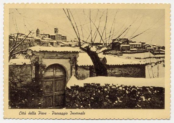The image displays a postage stamp featuring a monochromatic photograph of an old town during winter. The scene captures the quiet and serene atmosphere typically associated with snowy days in rural or historic settings. Bare trees without leaves stand prominently against a backdrop of snow-covered roofs, suggesting it is late fall or early spring due to their leafless state.

In the foreground, there's a partially covered archway leading into what appears to be an old building, possibly part of larger structures like churches or town halls common in European towns. The architecture suggests historical significance with its aged walls and simple designs characteristic of older construction styles.

The background shows multiple buildings clustered together, each topped with snow, hinting at the cold weather conditions prevalent during this time. A church tower is visible on the left side of the image, indicating a possible central communal building within the town's layout.

A handwritten inscription along the bottom reads "Città della Pieve - Paesaggio Invernale," which translates from Italian to English as "City of the Vows - Winter Landscape." This label suggests that this stamp represents Città della Pieve, an actual location. The overall condition and style imply it's a historical or vintage image.

The postage mark on the top right corner indicates usage for mailing [...]