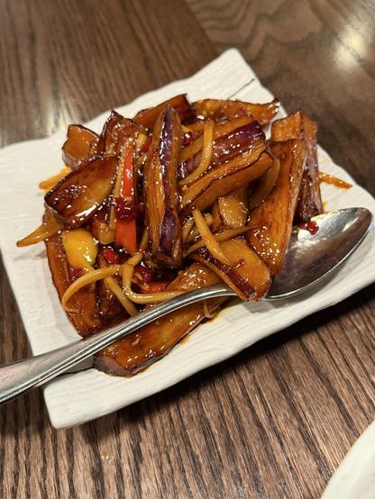 Plate of braised eggplant plant with a large spoon