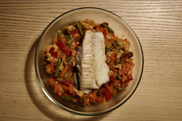 A plate of stir-fry vegetables with a piece of fish fillet on top.