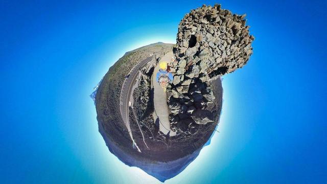One of a series of photos showing a person hiking around a lava rock field in the Willamette National Forest of central Oregon, often observing distant mountains on the horizon, all under clear blue skies.