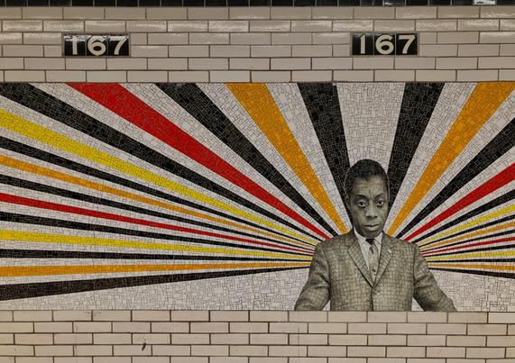 A subway tile art at the 167th Street stop in The Bronx depicting James Baldwin. Yellow, black, and red colored stripes emanate from Baldwin’s being.