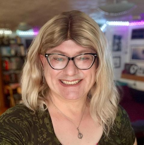 Candid color photo of Tim Melody Pratt, a fair-skinned woman with glasses and long blonde hair. She grins into the camera.