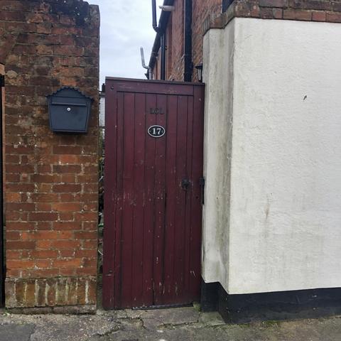 A tall wooden garden gate, with a plaque with the number 17 on it. The letters LCL have been individually added above it.