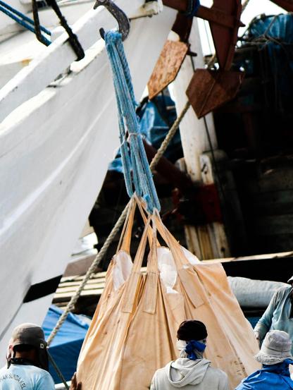 Photograph of a group of people standing on a dock next to a boat in Jakarta. By Pradamas Gifarry under a free Unsplash license: https://bit.ly/49JxOvU