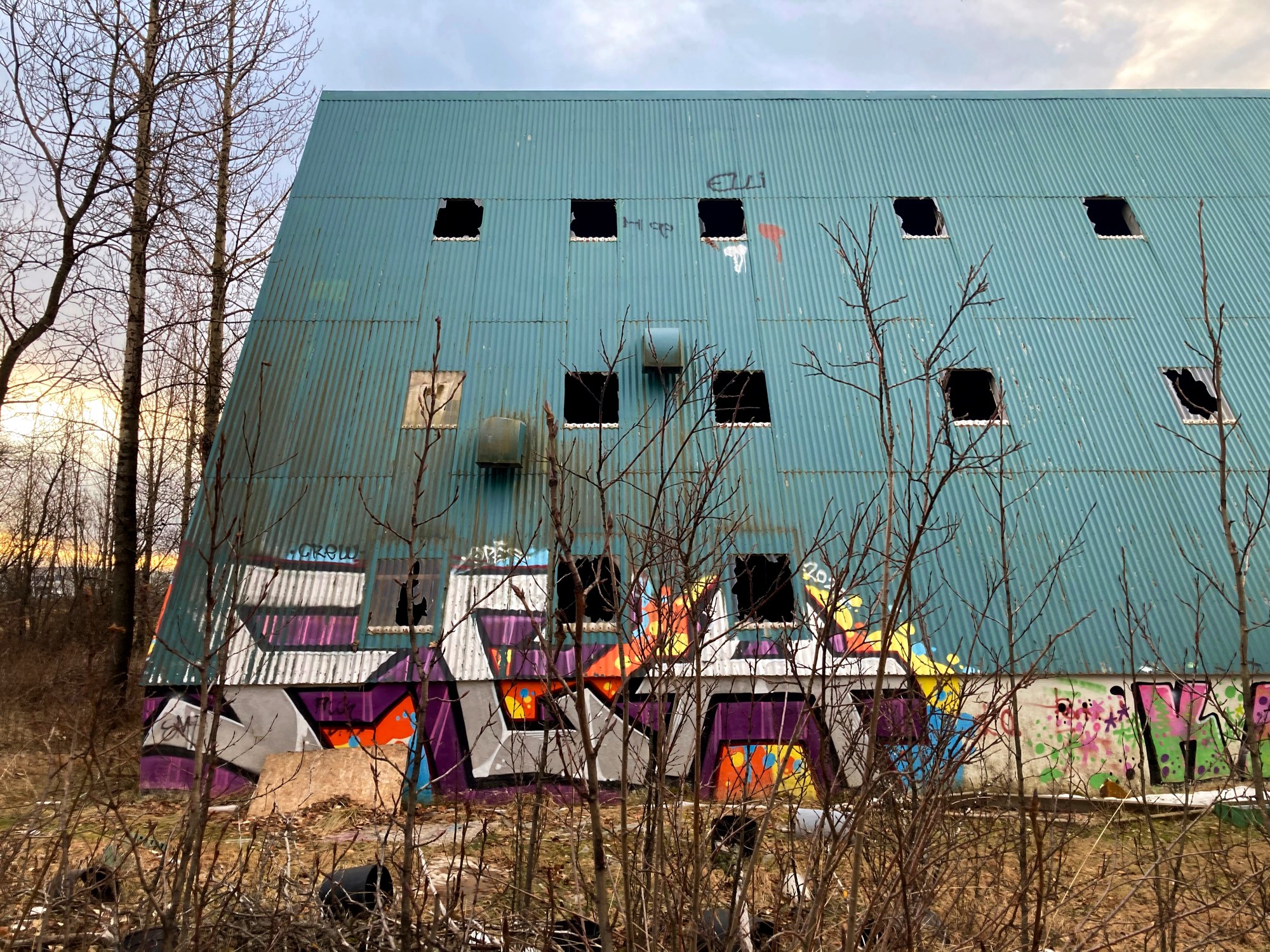 The side of an abandoned A-frame building covered in graffiti.