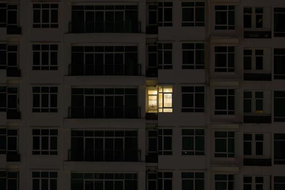 Imagen de archivo de la fachada de un edificio con solo una vivienda con la luz encendida. (Getty Images)