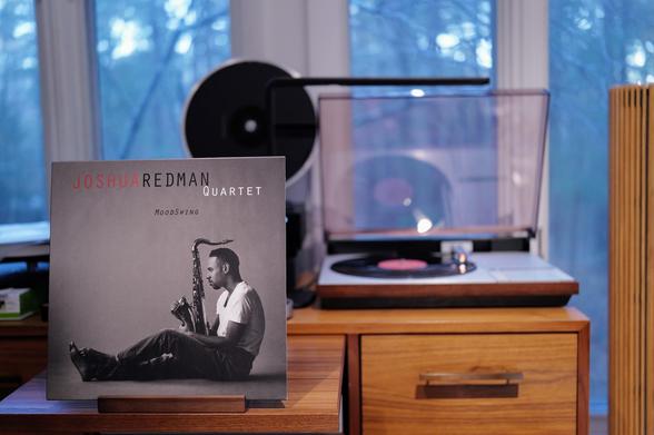 Joshua Redman Quartet - MoodSwing LP cover.

A "moody" shot of Redman, in profile, holding his sax, whose mouthpiece extends over his head.

The black LP plays on a vintage, restored Bang & Olufsen Beogram 4000 linear-tracking turntable to the right.