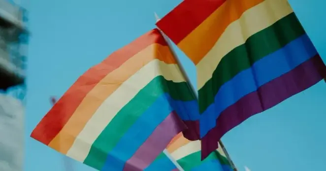 The image shows two pride flags against a blue sky backgroud. The image is chosen to represent the article's focus on the Kazakhstan ban on LGBTQ+ 'propaganda'