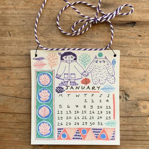 The January page of the calendar featuring Tso and Fraser holding hands, leaves, and patterns.