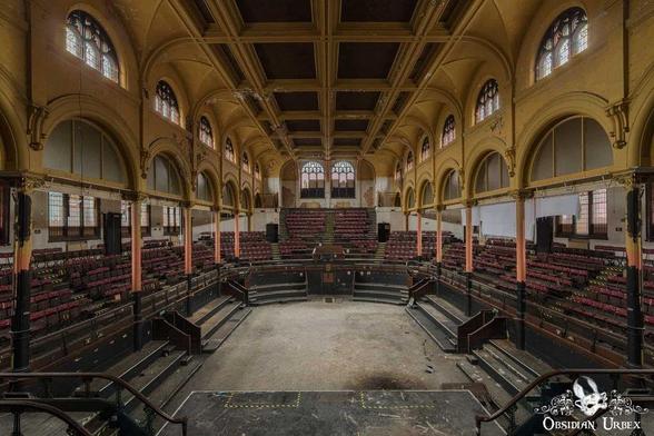 auditorium or hall, featuring ornate, high-arched ceilings and multiple levels of seating balconies. The architecture is grand, with Victorian-era design elements