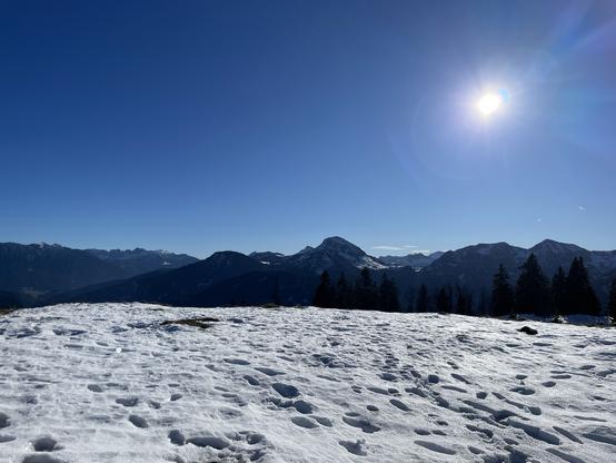 Sonniges Alpenpanorama, im Vordergrund Schnee mit Fußspuren