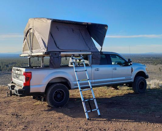 Picture of a different brand of roof-mounted tent system on a pickup truck. A short ladder leads up inside the tent.