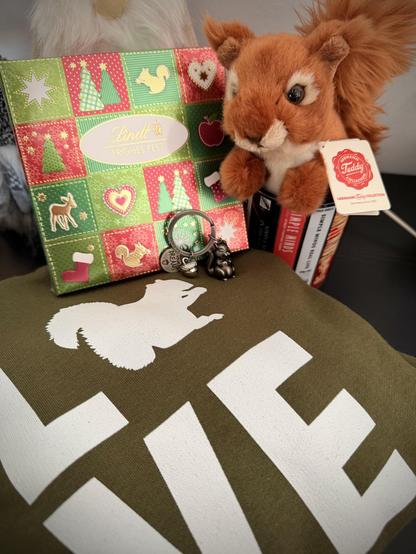 Weihnachtsgeschenke: ein Hoodie mit dem Aufdruck LOVE, das O ist ein 🐿️. Dazu ein 🐿️-Schlüsselanhänger und eine 🐿️-Plüschfigur. Auch die Schokolade hat einen Hörnchen-Aufdruck.