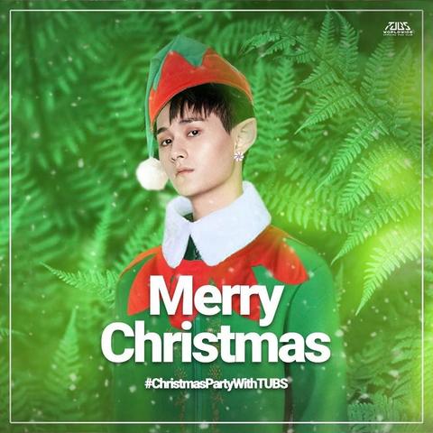 Ji Li dressed as a Christmas elf in red and green, fading into a background of bright green ferns and throwing the camera a knife-sharp look of sexy disdain. His visible ear is pointy and wearing a diamond stud.