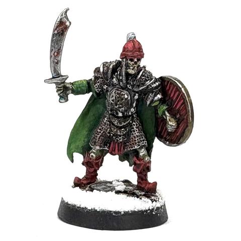 Skeleton Warrior in greens and reds wearing layers of rusty chain armor holds a sword and shield. He is merry.