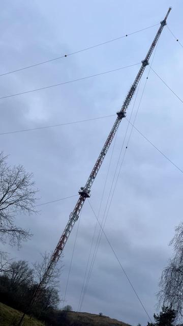 Funkturm Diagonal im Bild, der mit zahlreichen Seilen am Boden fixiert ist.