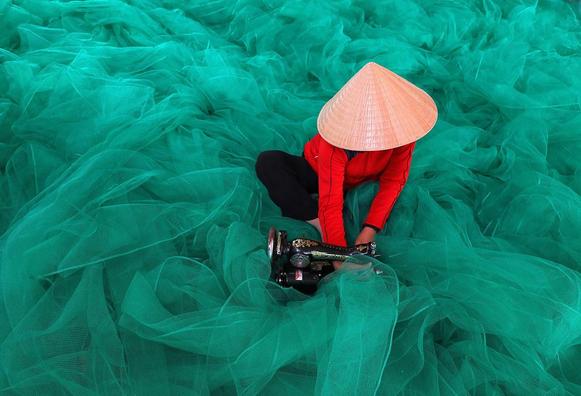 Vietnamese woman  mending large fishing nets in Nha Trang.
