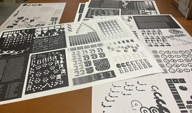 Printing sheets in the table at the printing workshop. The pages each show one to five letters in different stages.