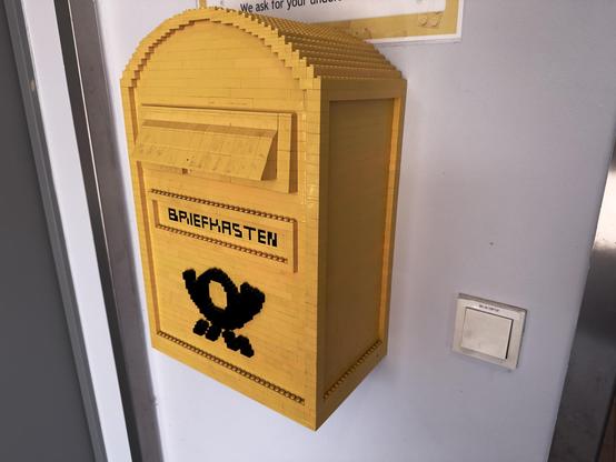Ein gelber deutscher Briefkasten der aus Legosteinen gebaut wurde.