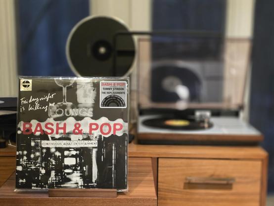 Bash & Pop - Friday Night is Killing Me LP cover.

A shot of what I assume is the adult entertainment district of Milwaukee, with Bash & Pop in red in the center. Handwritten in the upper left - "Friday Night is Killing Mme".

The black LP plays on a vintage, restored Bang & Olufsen Beogram 4000 linear-tracking turntable to the right.
