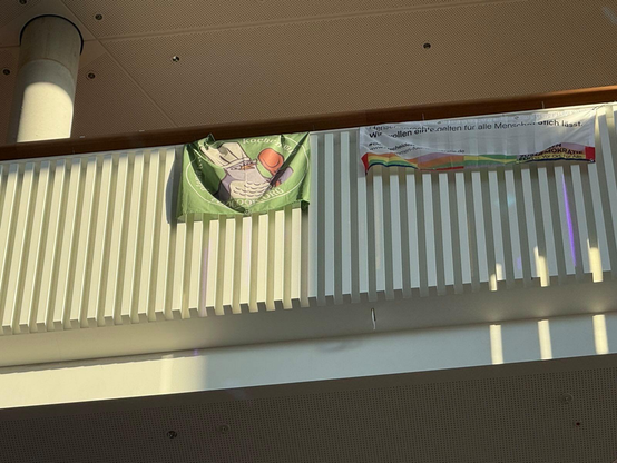 Photo from below to a railing with two flags, one of which is the Coocook.org flag