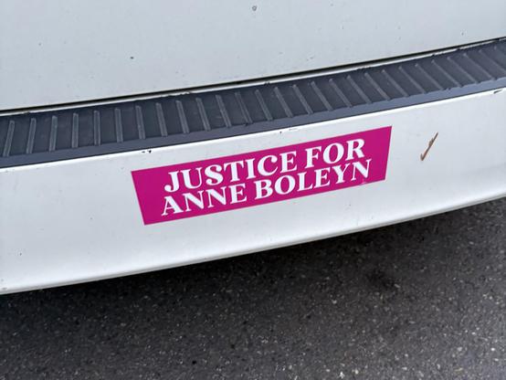 Photo of white bumper sticker with magenta bumper sticker reading “Justice for Anne Boleyn” in large serifed capital letters.