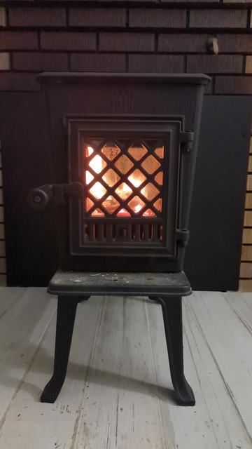 A small Jotul wood stove with a fire blazing inside.