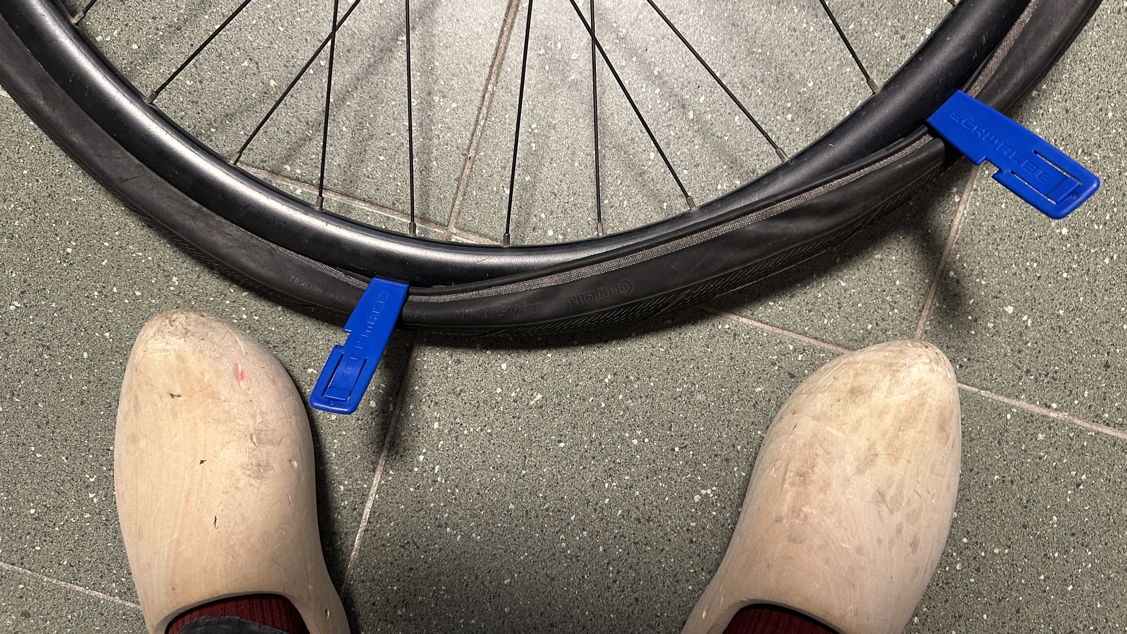 Bicycle tire almost all the way on with two irons wedged to try to force it the last few cm.