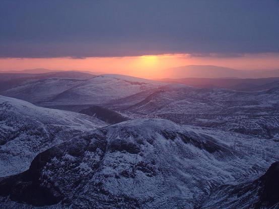 The sun is low over the snow covering The Mourne Mountains. Only snow and sunlight is visible. Haunting, still and silent landscape.