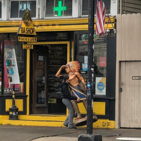A young woman carries a "cigar store Indian".