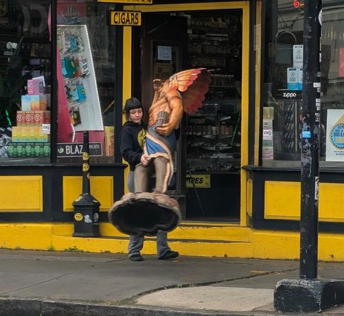 A young woman carries a "cigar store Indian".
