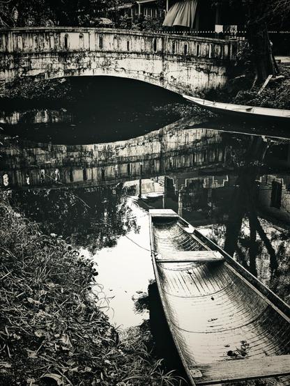 An ancient footbridge arches over a canal with water so still, the reflections themselves seem to have their own gravity