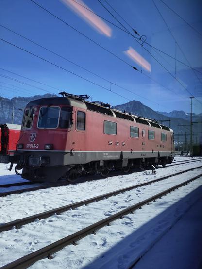 Foto. Eine rote Lokomotive im Bahnhof.