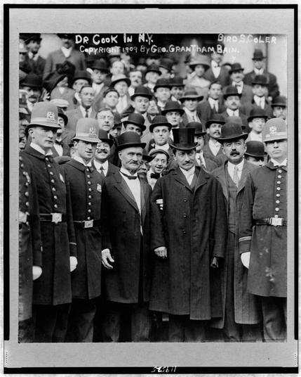 The image is a black-and-white photograph, likely from the early 20th century, judging by the clothing and style of the people. It appears to be a formal group photograph, possibly taken at a public or official event. The photograph is framed with a thin border and has handwritten text at the top and bottom.

At the top of the image, the text reads: "DR COOK IN N.Y." and "BIRD S. COLER". At the bottom, the text states: "COPYRIGHT 1909 BY GEO. GRANTHAM BAIN."

The group is composed of men dressed in formal attire. Most of the men are wearing suits, ties, and hats. The central figure in the photograph, who appears to be the focal point, is dressed in a long coat and a top hat. This individual is standing in front of a group of men who are also dressed formally, with some wearing uniforms that suggest they might be part of a police or military unit. The uniforms have distinct badges and insignia, indicating a sense of authority or official duty.

The background is filled with more men, also dressed formally, and some are wearing top hats. The overall composition suggests a significant event or gathering, possibly related to a public figure or a significant occasion in New York City in 1909. The photograph captures a moment of formality and importance, with the central figure and the group behind him standing in a way that suggests they are posing for a photograph.