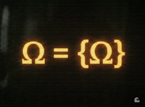 Amber phosphor CRT screen displaying the equation Ω = {Ω} — the Quine atom, a self-containing set. Horizontal scanlines visible across glowing mathematical notation.