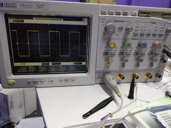 a 4-channel HP oscilloscope, displaying a square wave. it has a bunch of normal oscilloscope stuff, like knobs and buttons and a floppy drive