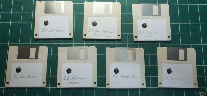 Seventan 3.5" floppy disks on a green cutting mat. They all have labels with the NeXT logo printed on them in color and handwritten text in pen. They read: 3.3 Beta Drivers, 3.3 Boot Disk Moto (Back Hardware), 3.3 Boot Disk (Intel), 3.3 Core Drivers, 3.3 Additional Drivers, 3.3 PCCard Drv, and 3.3 Driver Disk.