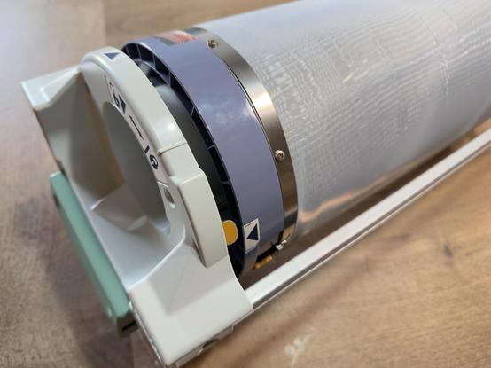 A newly refurbished Riso ink drum resting on a wooden countertop surface