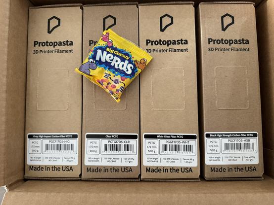 Four boxes of Protopasta 3D printer filament, each 1/2 kilo of PCTG: grey high impact carbon fiber, clear, white glass fiber, and black high strength carbon fiber. Also a fun size bug chewy nerds package.