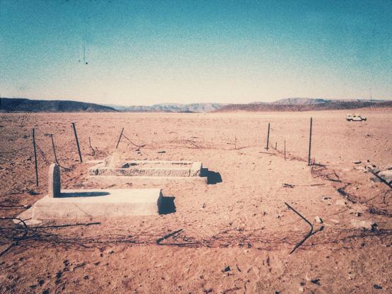 Two neglected graves, surrounded by a destroyed fence.