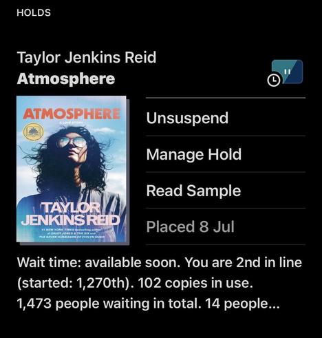 A screenshot of the book cover of  "Atmosphere" by Taylor Jenkins Reid. It includes options like "Unsuspend," "Manage Hold," and "Read Sample." The wait time is indicated as 2nd in line with a total of 1,