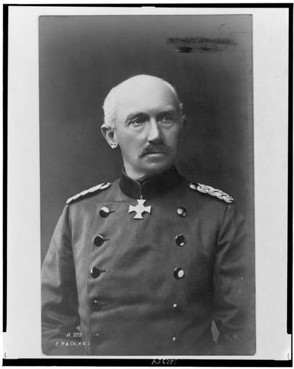 The image is a black-and-white portrait of a man in military attire. He is wearing a uniform with epaulets on the shoulders, indicating a rank, and a cross medal or decoration pinned to the left side of his chest. The uniform appears to be from the early 20th century, given the style of the epaulets and the overall design. The man has a mustache and is bald. The photograph has a border with text at the bottom right corner that reads "A 222" and "E.P.&Co., A.G.L." This suggests it is a professional photograph, likely taken by a specific studio or photographer. The style of the photograph and the uniform suggest it could be from the World War I era.