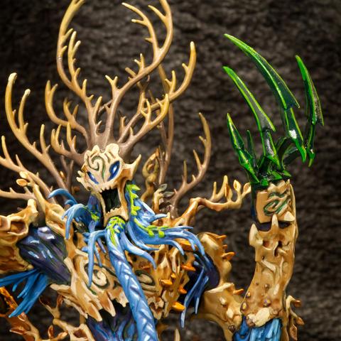Handpainted model of a brown tree creature with a blue beard and green claws against a dark background.