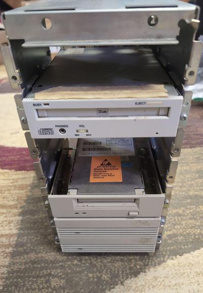 The front of the case with the outer shell removed. The top drive bay is empty. The CD reader has a strip of ancient masking tape on the top of it. The tape drive has a static warning sticker on it.
