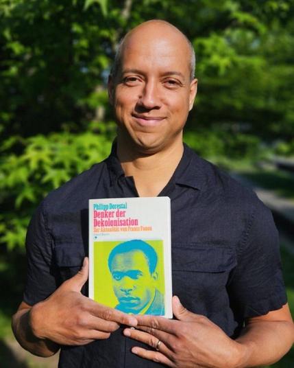 Philipp Dorestal hält sein neues Buch in Händen: »Denker der Dekolonisation. Zur Aktualität von Frantz Fanon«