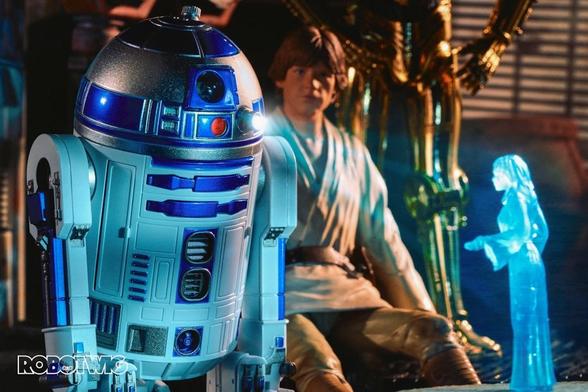 R2 D2 projects a hologram of princess leia whilst Luke sits and watches, C3PO is stood behind Luke