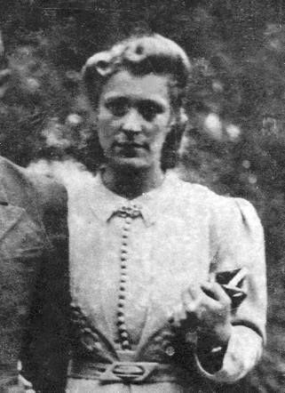 A black and white photo of a woman in a buttoned-up shirt and a decorated collar.