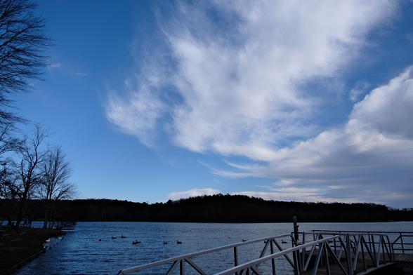 A dramatic white cloud patterns in a blue sky over a lake